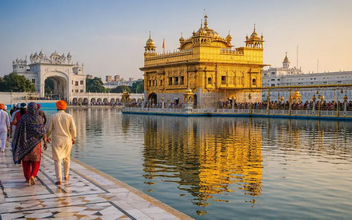 Golden Temple in Amritsar reflecting in the sacred Amrit Sarovar with devotees walking along the marble pathway.
